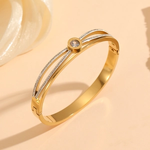 Detail of gold-plated bangle featuring Roman numeral disc and paved cubic zirconia stones