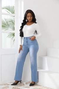 Détail d'un jean taille haute porté avec un haut en maille blanc et des talons noirs