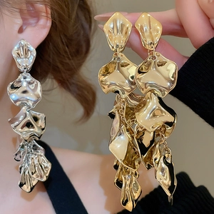 Detail of long metal tassel earrings in gold and silver finish on model