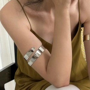 Close-up of a wide polished silver metal upper arm cuff on a female model