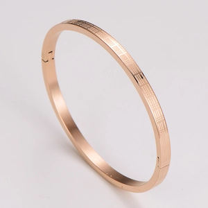 Detail of rose gold open cuff bracelet featuring an engraved classic lattice pattern