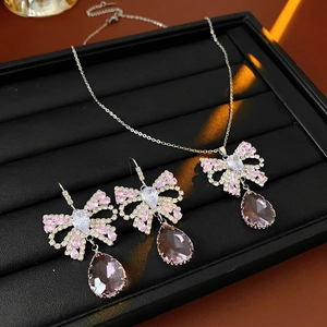 Detail of bow-shaped jewelry set featuring pink zircons and purple teardrop gemstones