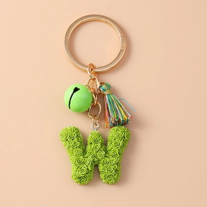 Detailed view of green rose-textured W letter keychain with bell, tassel and gold ring