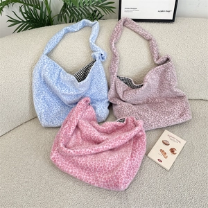 Plush leopard print tote bags in pink and blue displayed on a soft textured sofa