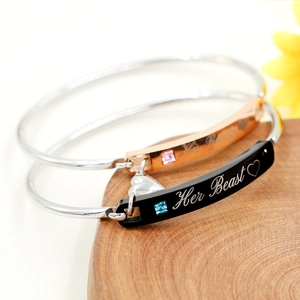 Close-up of His Beauty and Her Beast couple bracelets with engraved heart pendants