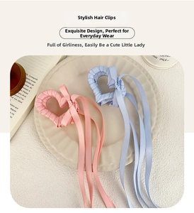 Dettaglio di fermacelli per capelli a cuore in nastro di raso rosa e blu con nappe