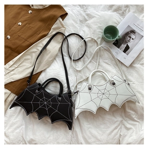 Detail view of Gothic bat wing PU bag with spider web embroidery on white linen backdrop