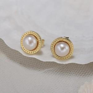 Close-up of elegant freshwater pearl earrings with golden wheat texture base on lace