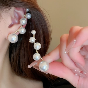 Elegant gold cuff earring with gradient white pearls displayed on ear and hand