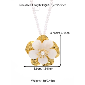 Golden camellia flower pendant necklace with white petals and a pearl center on white backdrop