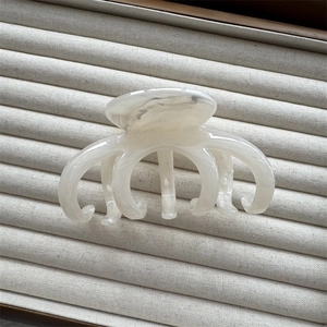 Detail of white marble textured hair claw clip on a minimalist fabric display tray
