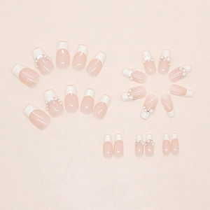 Macro detail of French press-on nails featuring white tips and elegant pearl accents