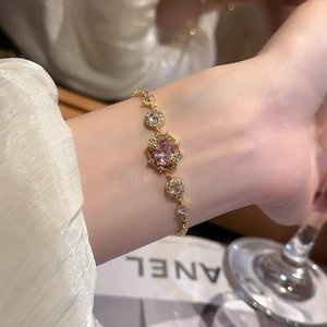 Detailed view of an 18k gold plated bracelet with pink oval gemstone on model's wrist