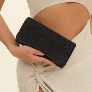 Detail of black glitter pleated evening clutch bag held by a model for weddings