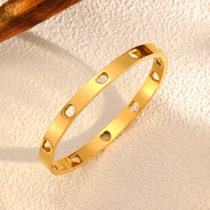 Détail macro du bracelet jonc plaqué or 18k avec motifs de cœurs évidés et fini poli