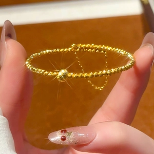 Detailed close-up of a 24K gold-plated beaded bracelet with an adjustable chain