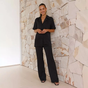 Detail of black satin loungewear set featuring button-down short sleeve shirt and long pants