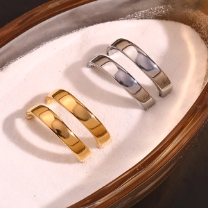 Close-up of double layered criss-cross rings in gold and silver finish on white sand