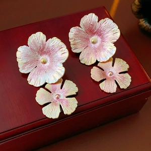 Detailed macro view of enamel flower earrings with pink gradient petals and gold center