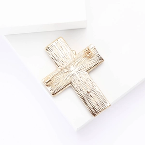 Close-up of the vintage gold cross brooch back side showing the pin and metal texture