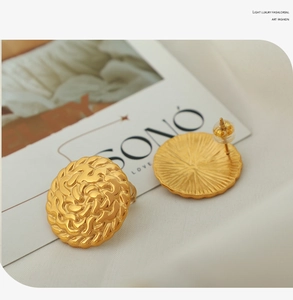 Detail of matte 18k gold stud earrings with intricate woven relief and brushed finish