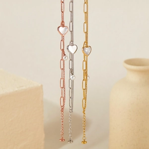 Detailed view of double-layer stainless steel bracelets with heart charms and pearls
