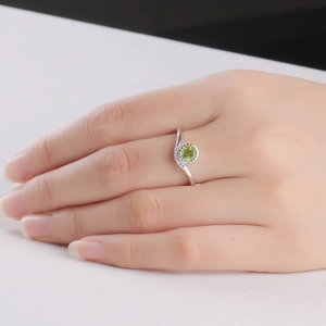 Close-up of 925 silver ring with round green peridot and micro-set diamonds on hand