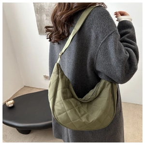 Detailed view of an olive green quilted crescent bag worn with a stylish grey coat