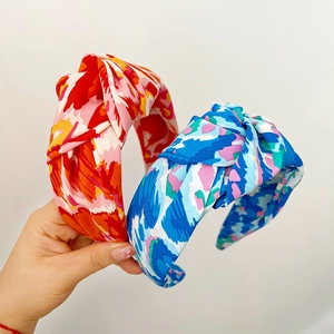 Close-up of two knotted headbands with vibrant floral prints and satin texture