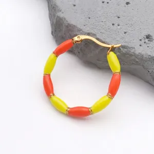 Detail view of gold-plated bamboo hoop earrings with yellow and orange enamel beads