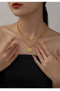 Detail of layered gold beaded chain and vintage portrait coin pendant on a model