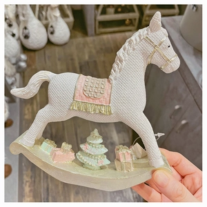 Close-up of white resin rocking horse ornament with knit texture and pink saddle detail