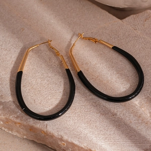 Detailed view of large gold oval hoop earrings with sleek black enamel inlay