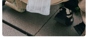Outdoor shot of a portable white mesh water bottle carrier with adjustable strap