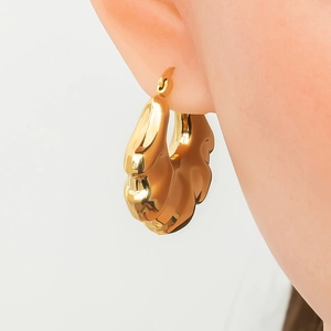 Chunky gold-plated hoop earrings with textured ripple design shown on a female model