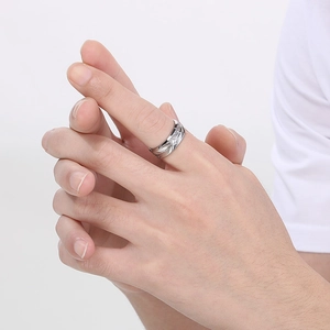 Close-up of a silver feather textured ring with a small diamond on a model's finger