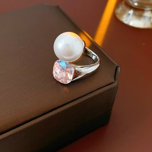 Detailed macro of silver-tone ring with white pearl and pink cushion-cut crystal