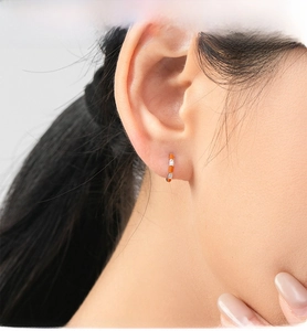 Close-up of bright orange S925 sterling silver hoop earrings with white zircon inlays