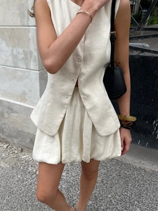 Ensemble chic gilet en lin crème et mini-jupe bouffante dans un décor extérieur épuré
