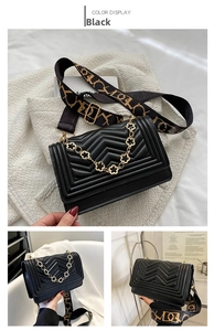 Detail of black quilted shoulder bag with golden flower chain and geometric pattern strap