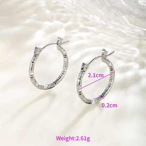 Macro shot of silver-tone hoop earrings with diamond-cut texture and 2.1cm diameter