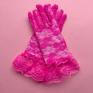 Macro detail of neon pink floral lace gloves featuring ruffled cuffs and intricate patterns