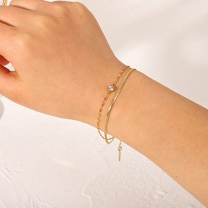 Dettaglio della catena a serpente dorata e del bracciale con pietra di zircone bianco