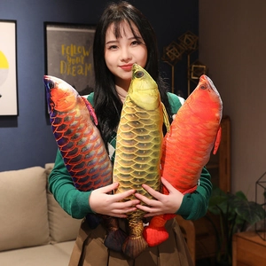 Detailed realistic plush fish pillows in three vibrant colors held by a person at home