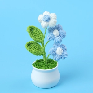 Detalle de flores de ganchillo azules hechas a mano en maceta de cerámica blanca y hierba