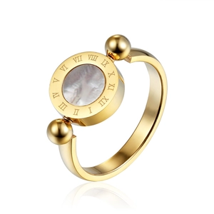 Detailed close-up of golden Roman numeral ring with white shell inlay and gold spheres