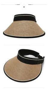 Close-up of straw open top sun hat with black fabric trim and metal G ornament