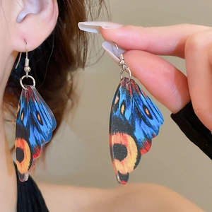 Detailed close-up of acrylic butterfly wing earrings with vibrant blue and orange textures