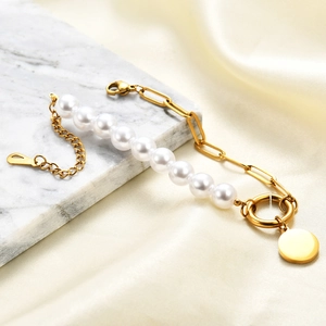 Detail of gold pearl bracelet with round pendant on marble and silk fabric background