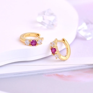 Detail of S925 silver gold-plated hoop earrings with pink gemstones and white zircons